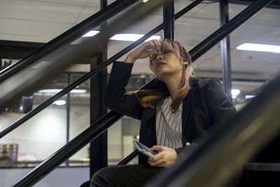 Stressed businesswoman sitting on steps at station