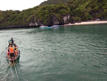 People in boat on river by trees