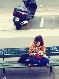 Woman sitting on sidewalk