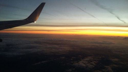 Aerial view of airplane wing against sky during sunset