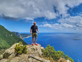 Man standing on rock against sky