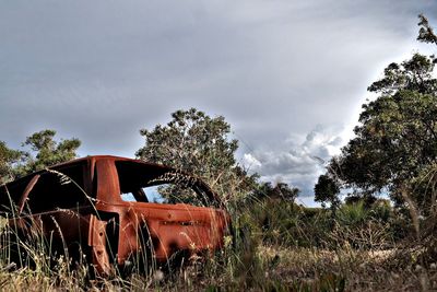 Abandoned vehicle on field against sky