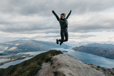 Full length of woman jumping on cliff