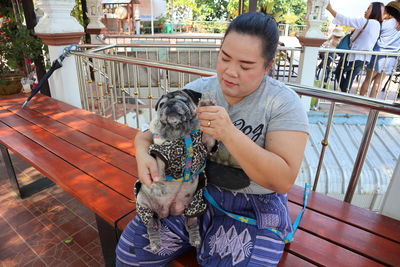 Overweight mid adult woman with dog sitting on bench in park