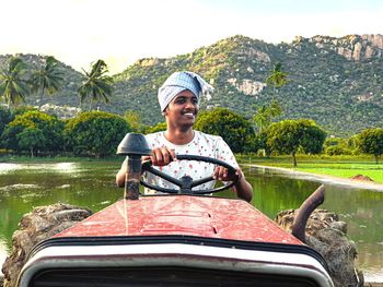 Portrait of young man sitting on boat against lake