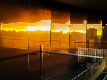 Buildings against sky during sunset seen through glass window