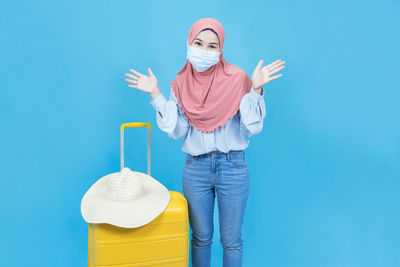 Young woman standing against blue wall