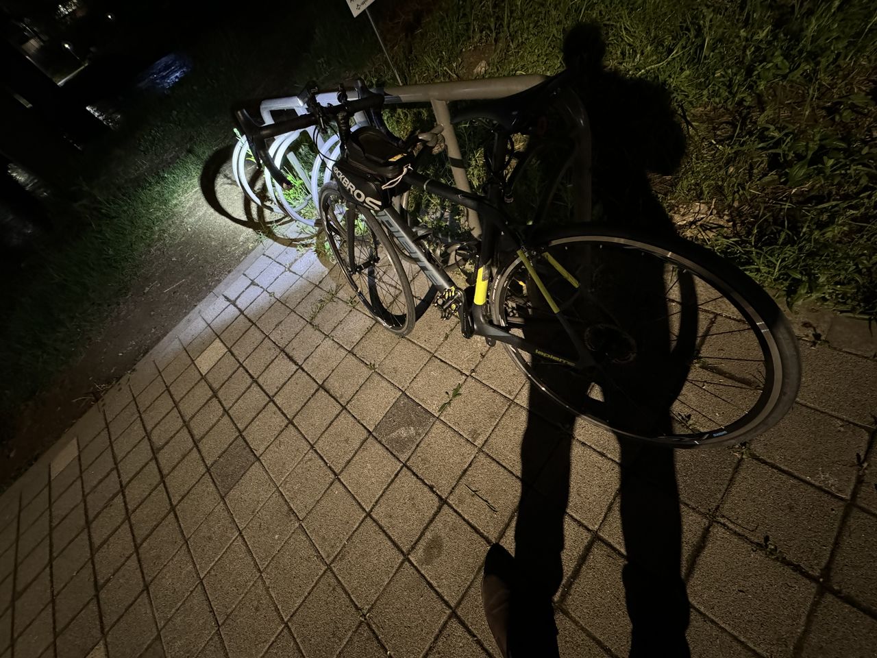 bicycle, darkness, transportation, night, black, light, land vehicle, mode of transportation, footpath, street, city, vehicle, shadow, high angle view, one person, nature, sidewalk, sports equipment, outdoors, wheel, cycling, architecture, lifestyles