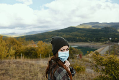 Portrait of beautiful young woman on land against sky