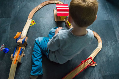 High angle view of boy playing with train set on floor at home