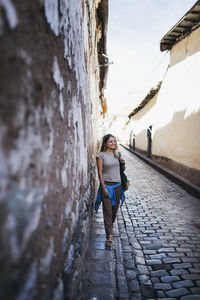 Woman standing on alley against wall