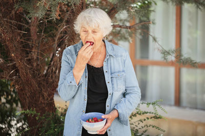 Elderly woman holding a bowl of ripe strawberries
