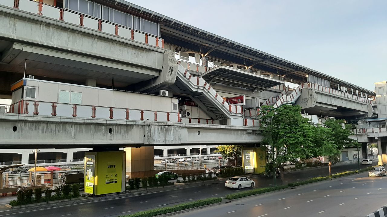 CARS ON ROAD BY BUILDING AGAINST SKY