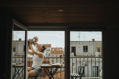 Mother relaxing with baby on balcony in summer