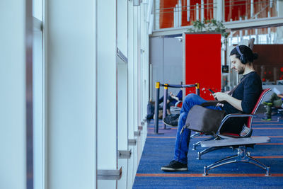 Side view of man sitting on chair at airport