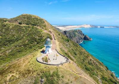 High angle view of lighthouse on mountain by sea against sky