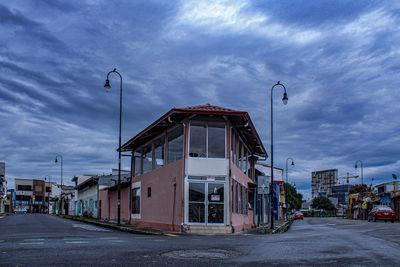 Empty road by building against sky