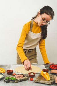 Caucasian teenage girl in an apron prepares pizza.