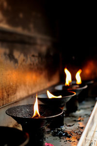 Close-up of lit diyas in temple
