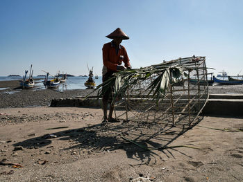 Rear view of man on beach against sky