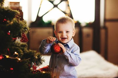 Portrait of happy toddler playing with christmas bauble at home