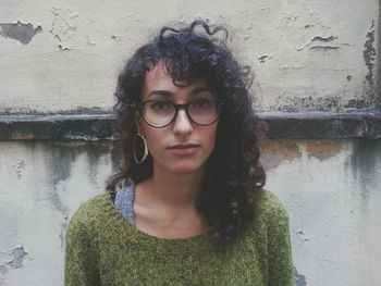 Portrait of beautiful young woman standing against wall