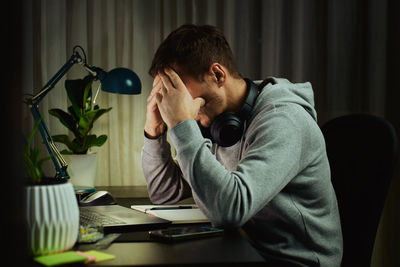 Side view of young woman using mobile phone while sitting at home