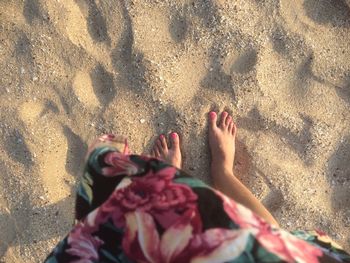 Low section of woman standing on sand at beach