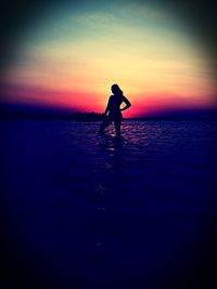 Silhouette man standing on beach against sky during sunset