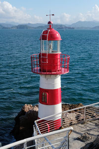 Lighthouse by sea against sky