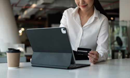 Midsection of woman using smart phone on table