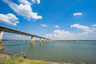 Bridge over calm river against sky