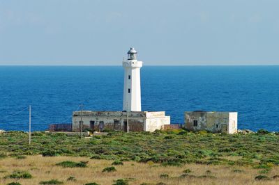Lighthouse by sea against sky