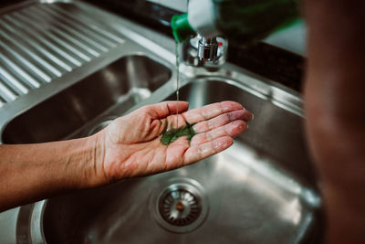 Cropped hands taking liquid in sink