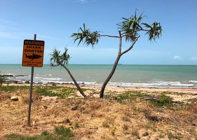 Information sign on beach against sky