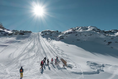 Panoramic view of people skiing on snowcapped mountain against sky