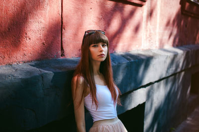 Portrait of young woman leaning on building