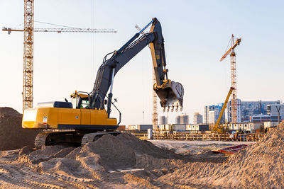 Cranes at construction site against sky