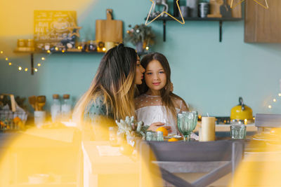 Mom kisses her daughter on the cheek at the festive christmas table