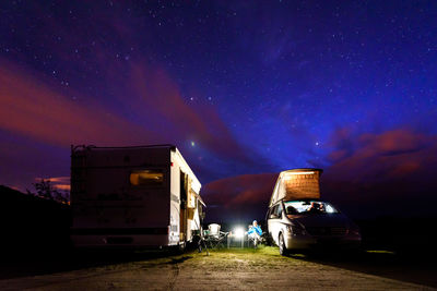 Motor home on field against sky at night