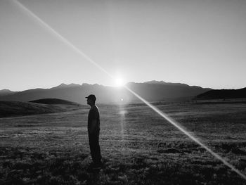 Man standing on field against bright sun