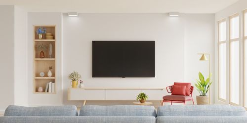 White wall mounted tv on cabinet in living room with red armchair and sofa,minimal design.