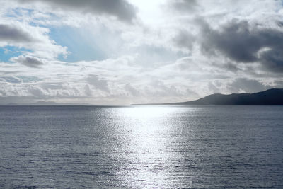 Sun beam reflection in the ocean . low clouds over the island