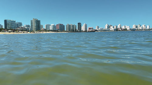 Sea and buildings against clear sky