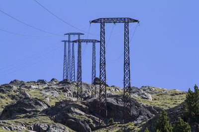 Low angle view of electricity pylon on mountain against sky