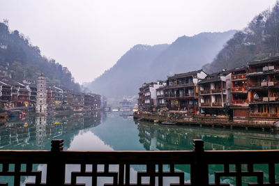 Buildings by lake against sky in city