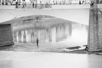 Reflection of man on bridge in water