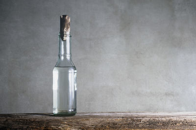 Glass bottle on table against wall