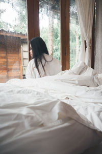 Young woman sitting on bed at home