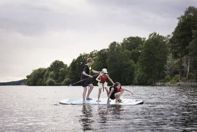 Siblings falling from paddle board on lake